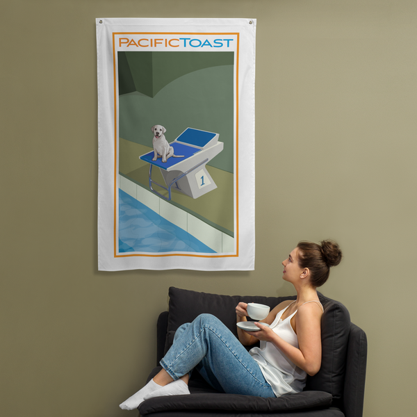 A sitting woman drinks coffee while admiring a wall banner illustrated with a cute, white Labrador puppy on a swim starting block