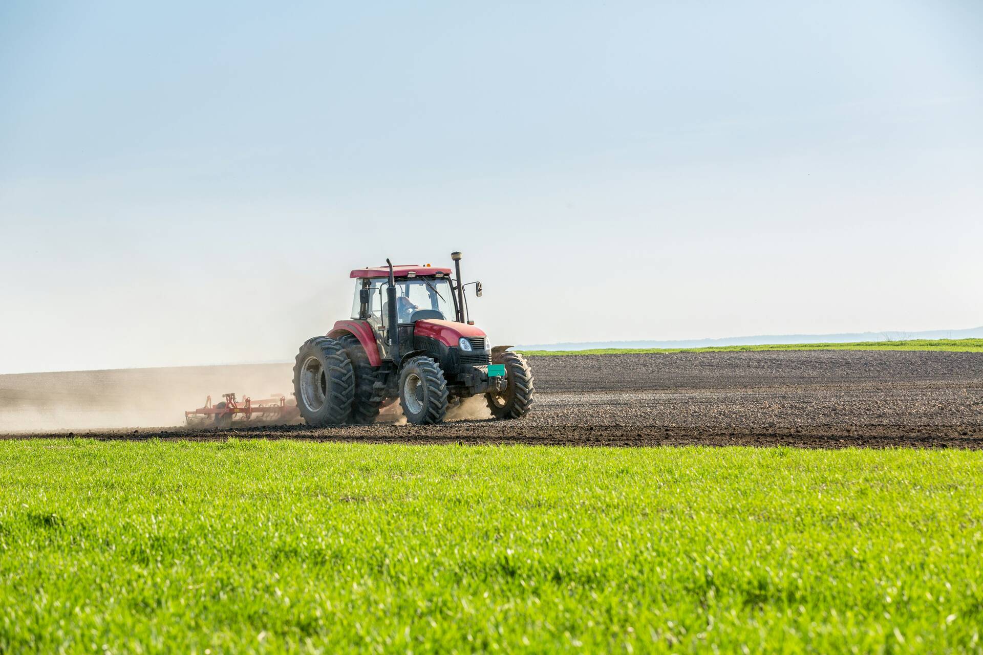 Red tractor cultivating a field