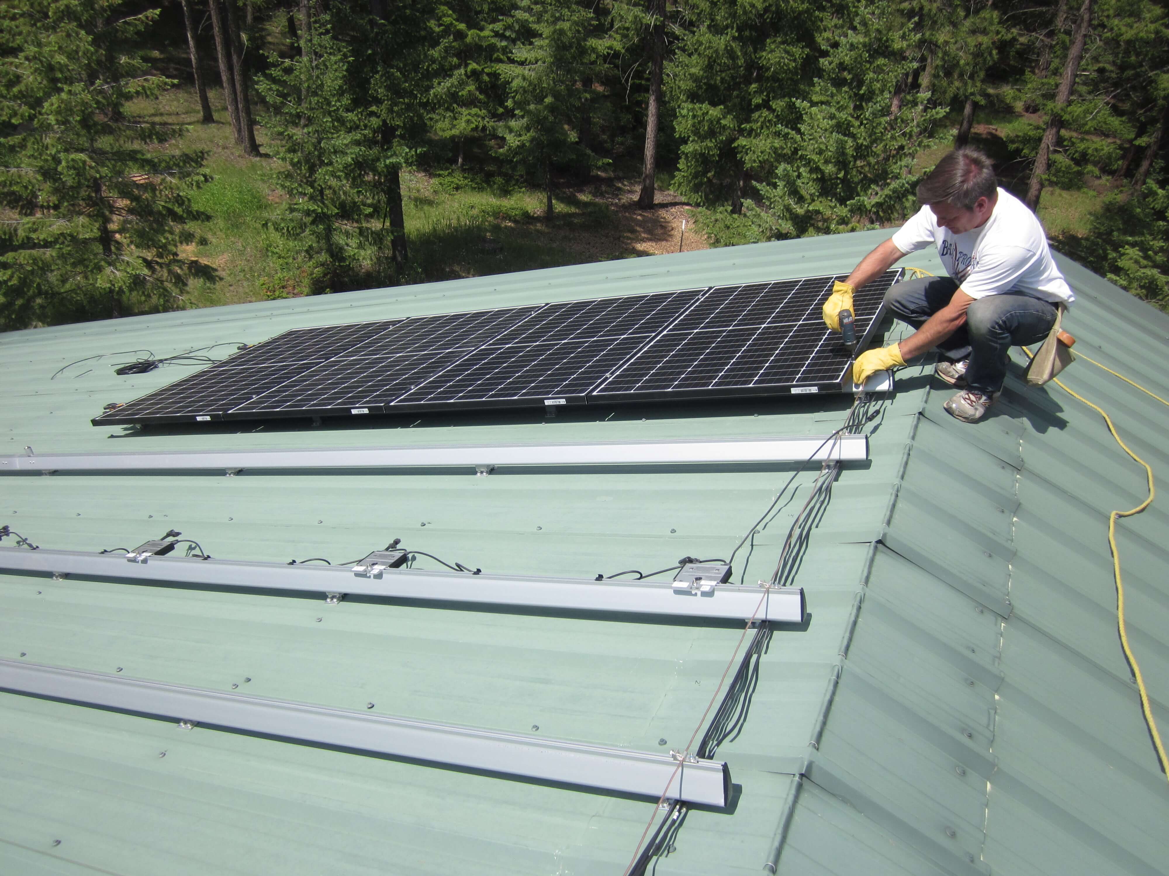 Homeowner installing solar panels on metal roof