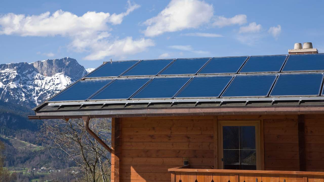 A cabin in the mountains featuring solar panels on its roof, blending sustainable energy with nature.
