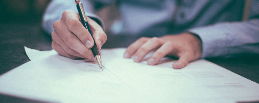 A person signing a solar installation permit, seated at a table with a pen