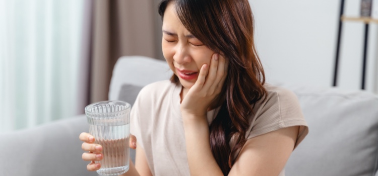 Woman holds her mouth in pain due to an oral blood blister.