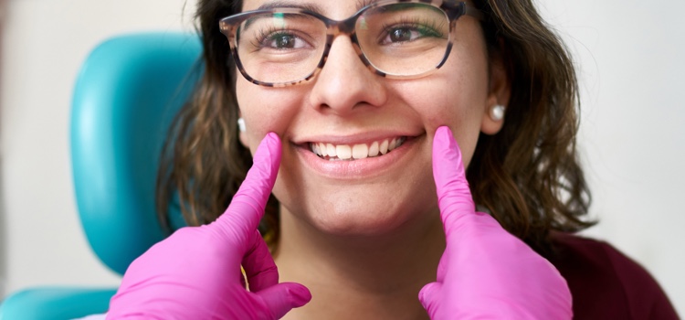 Dentist examining a patient's mouth whilst patient smiles