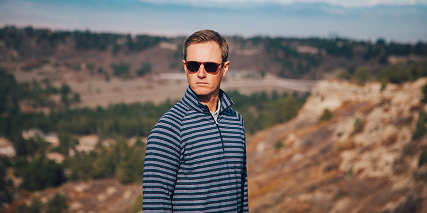 Man wearing jacket swinging golf club