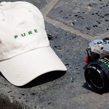 Imperial Headwear cap sitting on the ground next to a camera