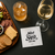 a Sipkin™ on a countertop with a glass of wine slightly overlapping it accompanied by a charcuterie board and a rocks glass filled with bourbon and ice