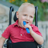 A child chews a royal blue MEGA Brick Stick™ Chew; a large, textured chew with big bumps on one side and small bumps on the other.
