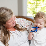 A mother and her son laugh while using the Baby Tetra-Bite for sensory exploration and development of the oral motor muscles.