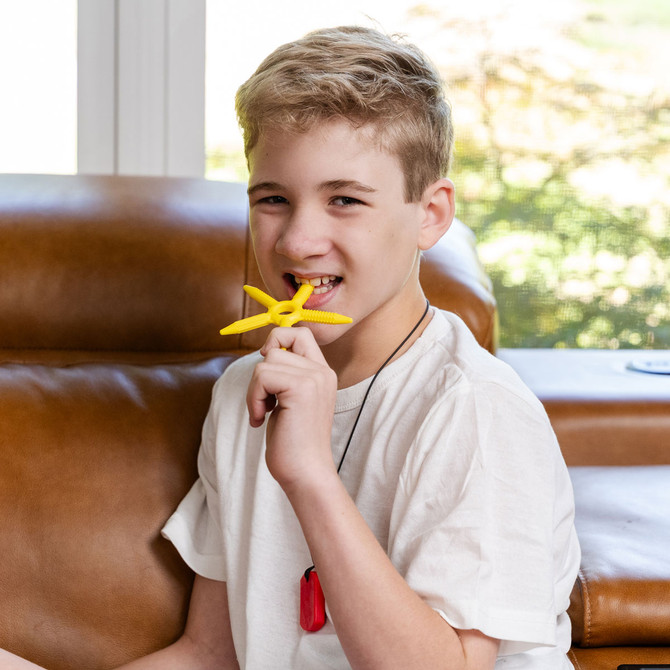 A pre-teen boy chews the Yellow SolaBite - a thin chew with 5 different textured extensions.