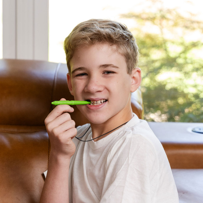 A pre-teen chews the Lime Green, Medium Chewable Pen Necklace, great for discreet back molar chewing.