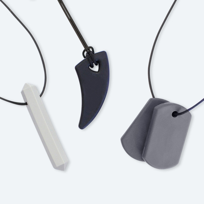 The ARK Chewelry for Adults variety pack comes in two styles, Original and New. Pictured is the Original - with the long and slender Krypto-Bite Gem Necklace, the Saber Tooth necklace with a wider base and tapered end, and the Chew Tags necklace, two thin dog tag shaped pendants.