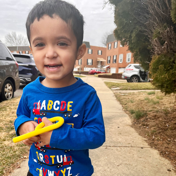 A child holds a yellow Grabber® P Tube (Hollow Chew Tool); a chew with a loop handle and hollow stem.