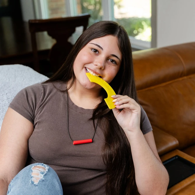 A teen chews the Yellow, Softest Rainbow Fidget.