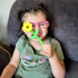 A child shows a yellow Flower Wand Chewy; a chew with a wide, robust flower shape on one end, and a long, slender stem on the other