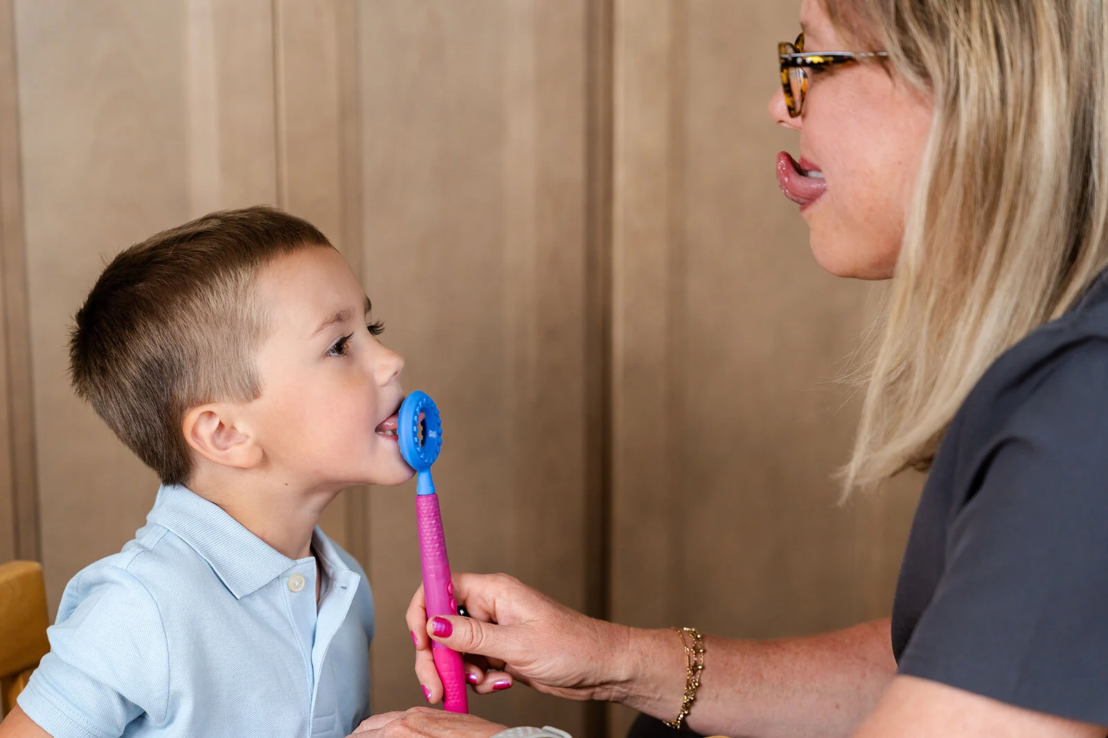 A young child bites gently on the blue Circle Tip of the Z-Vibe Plus during a supervised session.