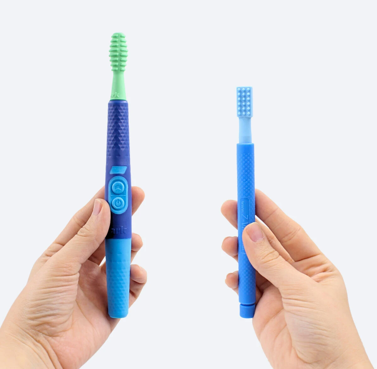 The Z-Vibe Plus on the left with its textured grip and buttons, and the original Z-Vibe on the right, both fitted with brush tips.