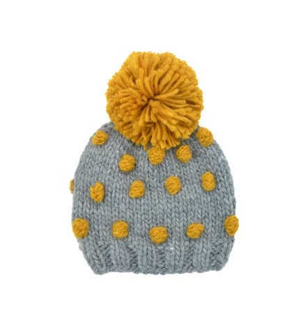 Stay cozy and stylish with The Blueberry Hill Popcorn Hat in a charming Gray and Mustard color combination.