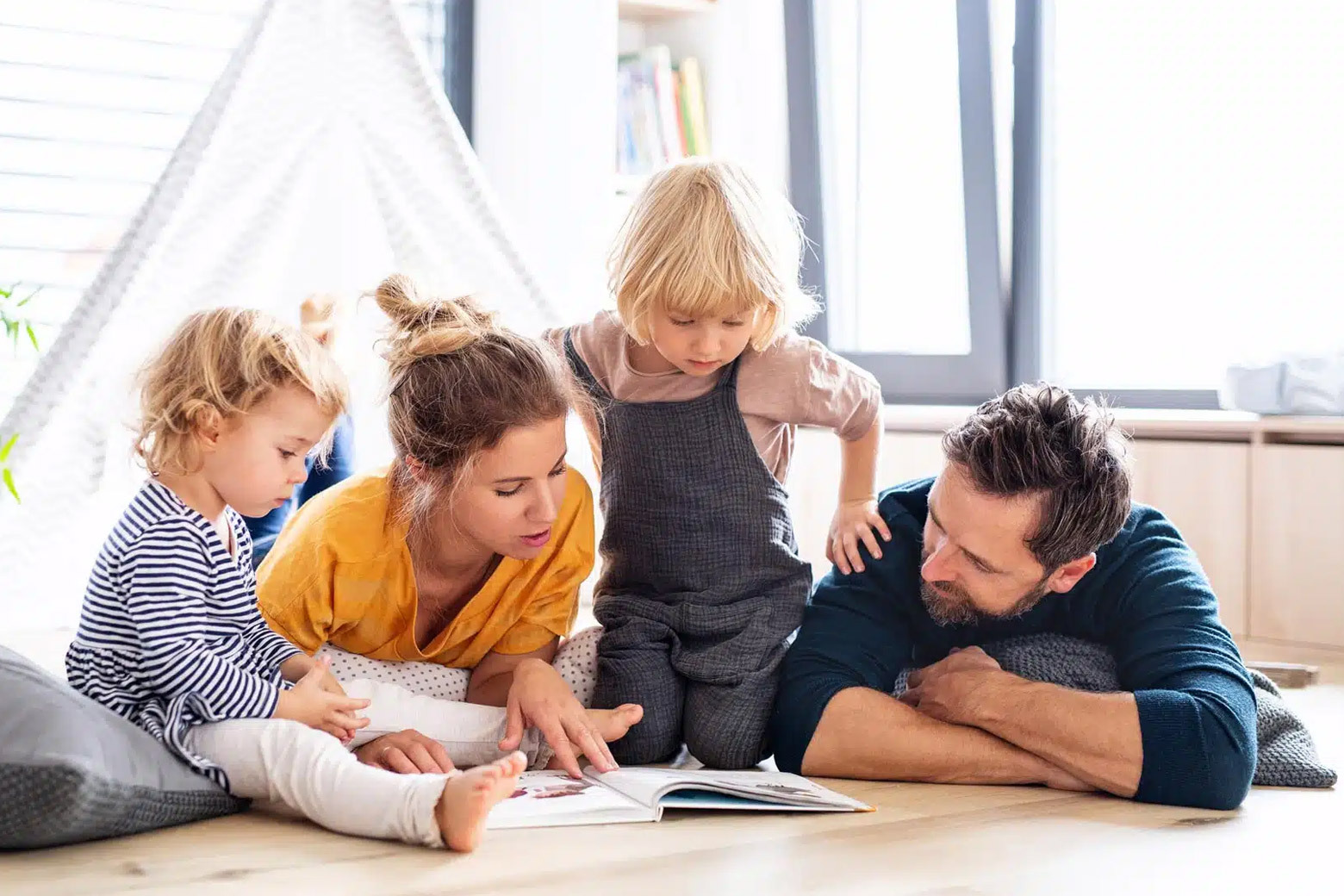 Family sitting comfortably on the floor while reading a book