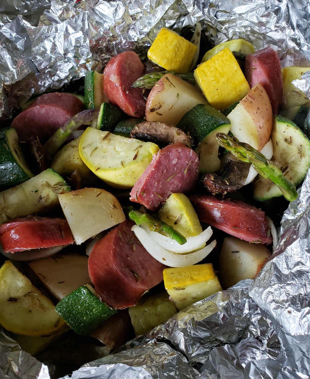 Luxemburg & veggies in foil pouch over campfire.