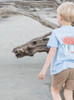 Boy wearing a stylish tee showcasing a vibrant depiction of a historic Crawfish Boil on the back