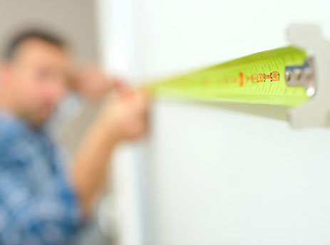 man measuring bedroom with measuring tape