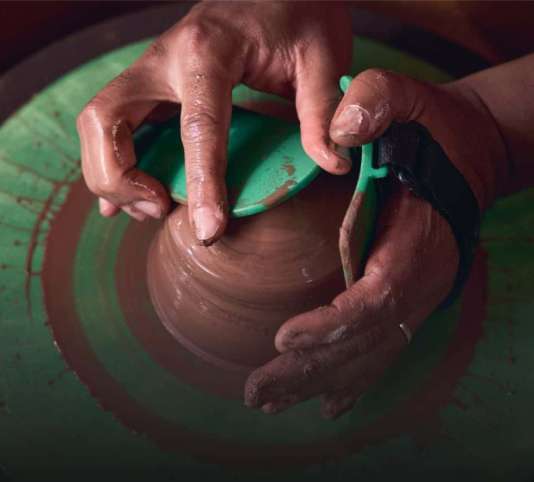 Close-up of hands on pottery wheel centering clay with Boss Ribs tools.
