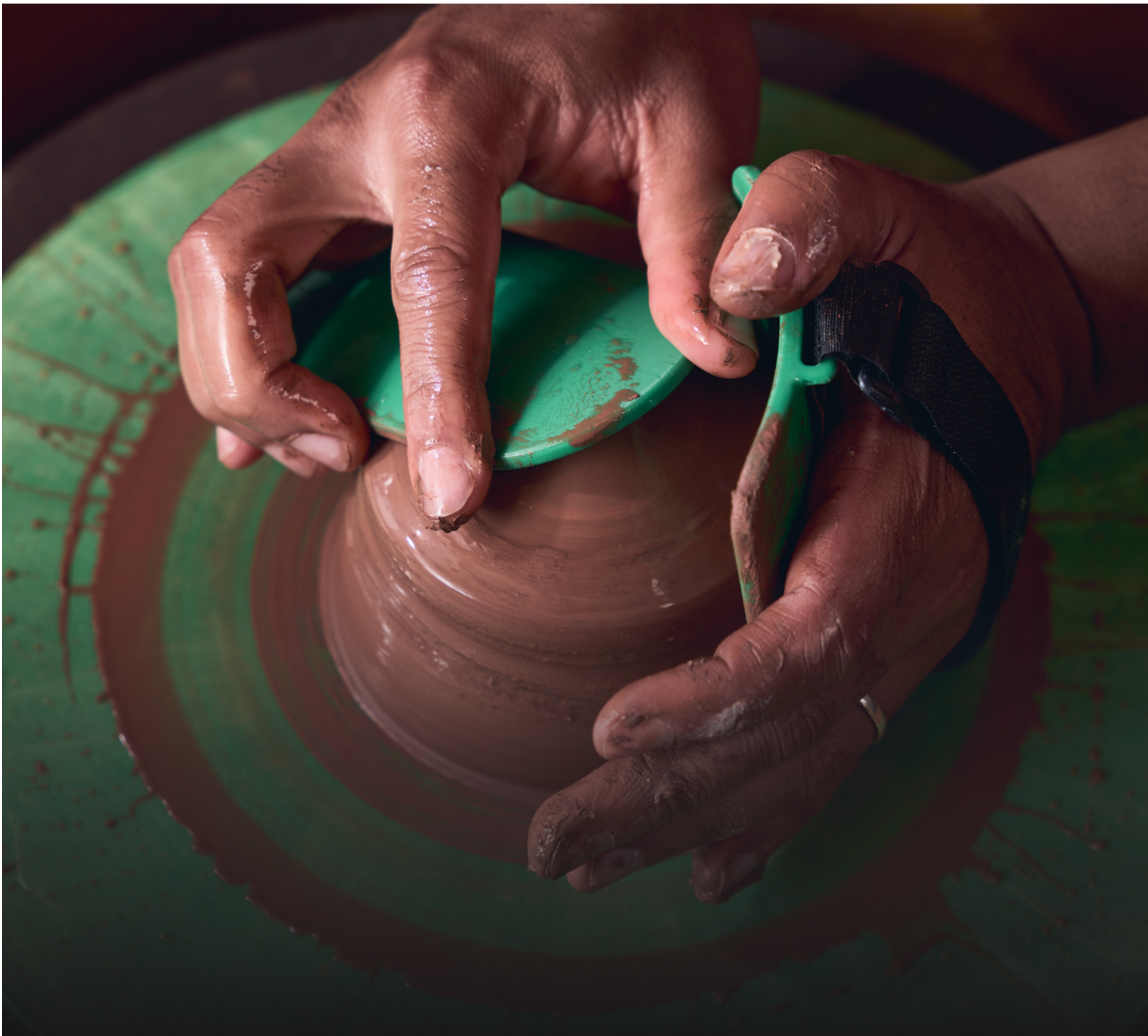 Close-up of hands on pottery wheel centering clay with Boss Ribs tools.