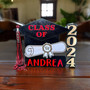 Custom graduation memento with a 3D cap design and a red tassel held by a magnet, centered over a diploma scroll that displays a school mascot and name.