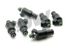 Set of six DeatschWerks 1200cc top feed fuel injectors, black bodies with green O-rings, angled view