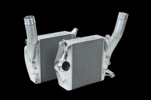 CSF raw aluminum intercooler pair with curved inlet pipes, front angled view, bare metal finish