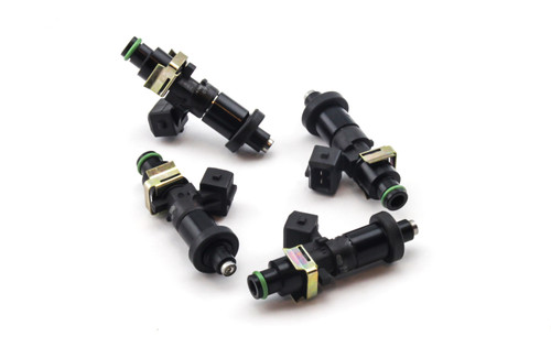 Set of four DeatschWerks EV14 1200cc fuel injectors, black bodies with brass clips, top down angled view.