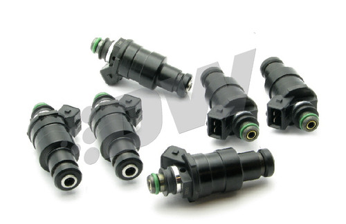 Set of six DeatschWerks 1200cc top feed fuel injectors, black bodies with green O-rings, angled view