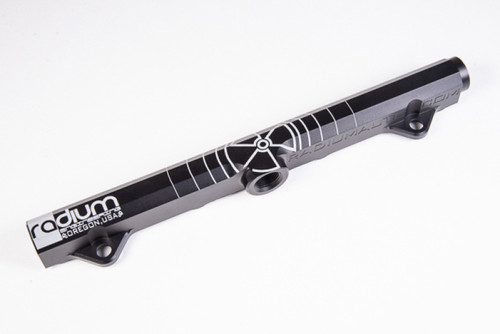 Radium Engineering fuel rail for Mitsubishi Evo 8-9, black anodized aluminum, angled view showing mounting tabs and fitting port.