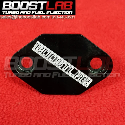 Boost Lab 2JZ-GTE cam angle sensor delete plate, black anodized hexagon block with two mounting bolt holes on red background