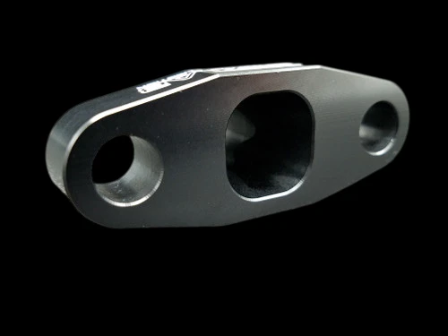 Boost Lab Billet T3/T4 Turbo Oil Drain Flange, black anodized, angled view showing three bolt holes and main oil passage