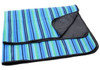 A striped picnic rug in blue, green, and black, featuring a black backing and a folded corner.