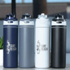 A drink bottle collection featuring navy, grey, white, and black recycled stainless steel with flip straw lids and branding.