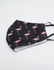 A black face mask with a pink flamingo pattern and an inner label, made of 100% cotton.