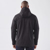 A black softshell jacket with a hood, featuring a logo, shown from the back on a model.