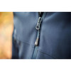 A close-up of a navy blue softshell jacket featuring a zippered front and a logo on the zipper pull.