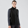 A black softshell vest with a zip front and side pockets, worn over a long-sleeve top. The model has a neutral expression.