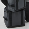 A dark grey cooler bag with sturdy straps, featuring a logo and a compact design for portable use.