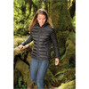 A woman in a black puffy jacket walks through a lush, green forest. The jacket features a zip front and a fitted design.