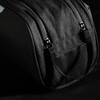 A black toiletry bag with straps and zippers, featuring a textured fabric and branding.