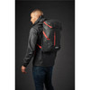 A black and red Whistler Backpack is worn on the back of a person in a dark setting. The bag features a logo.