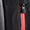 A close-up of a black softshell jacket featuring a red zipper and water droplets on the fabric. The jacket has a logo.