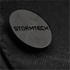 A close-up of a dark textured fabric featuring a circular black logo with the word "STORMTECH."