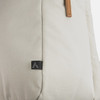 A beige backpack with a textured surface and leather accents, featuring a small logo on the side.