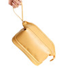 A yellow large capacity PU toiletry bag with a rounded shape and a handle, being held by a hand.