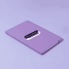 A purple A5 notebook with a smooth finish and a logo on the cover, lying flat on a light background.